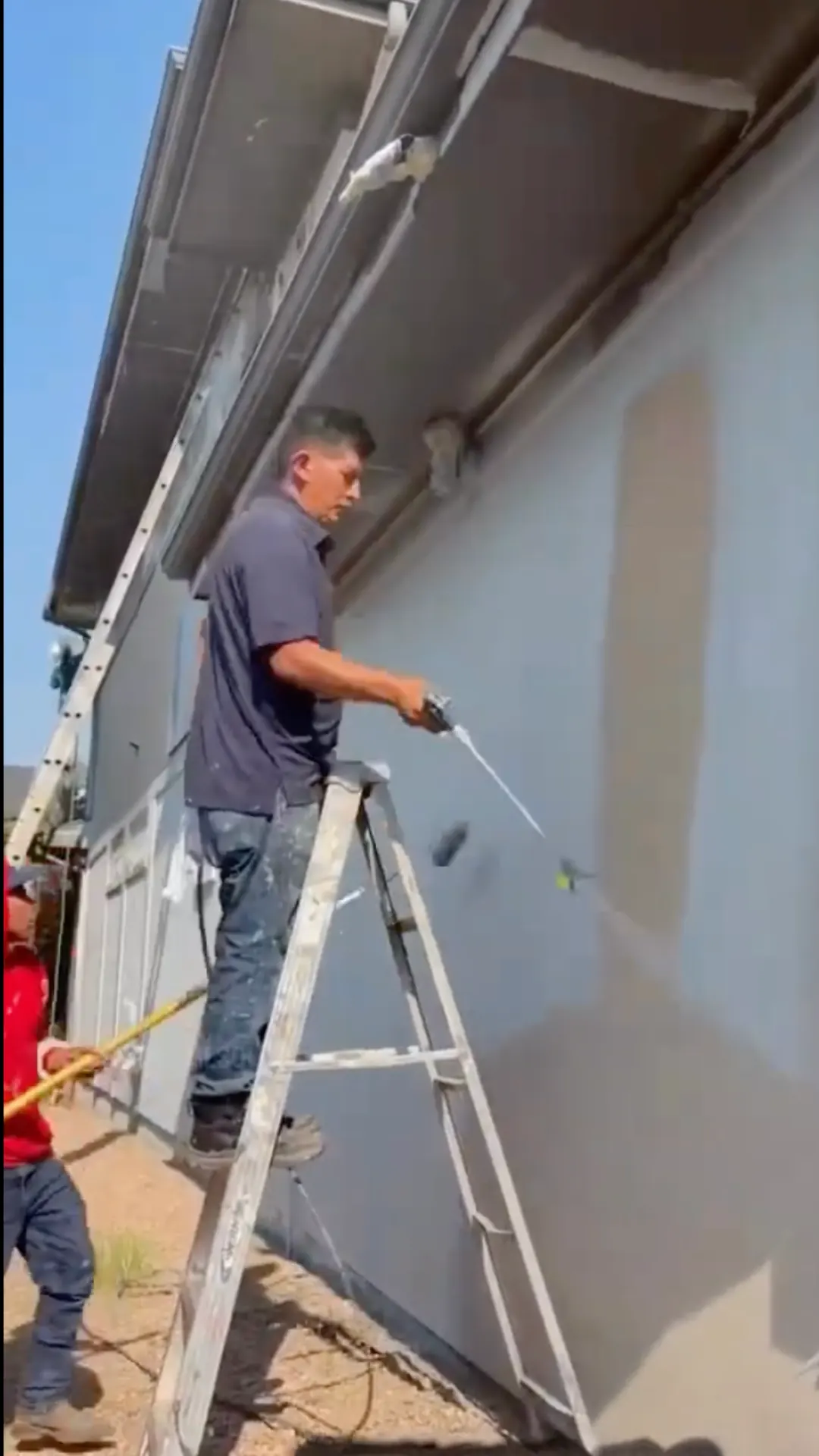 A Kind Home painter caulking under the eaves of a Denver home during exterior prep